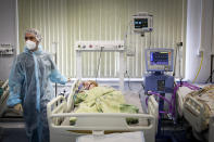 A medical staff member wearing a special suit to protect against COVID-19 treats a patient at an ICU in Infectious Hospital No. 23 in Nizhny Novgorod, Russia, on Wednesday, Oct. 20, 2021. The low vaccination rate in Russia, where only about a third of the population is fully vaccinated, is causing concern as the country suffers a sharp rise in cases, setting records for infections and deaths nearly every day this month. (AP Photo/Roman Yarovitcyn)