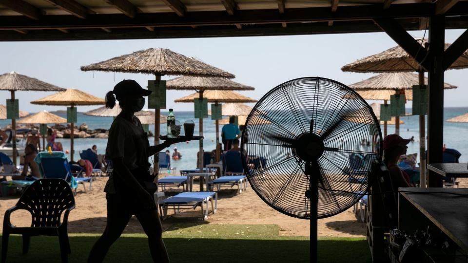 Eine Kellnerin serviert Erfrischungen in einer Strandbar im Dorf Lagonissi. Eine seit Anfang der Woche andauernde Hitzewelle in Griechenland erreicht ihren Höhepunkt.