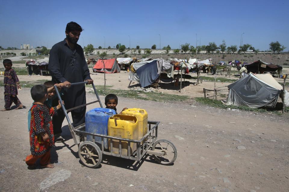 A man and small children walk to get drinking water from a nearby supply line on the outskirts of Peshawar, Pakistan, Wednesday, May 10, 2023. The flooding in Pakistan killed at least 1,700 people, destroyed millions of homes, wiped out swathes of farmland, and caused billions of dollars in economic losses. In Khyber Pakhtunkhwa, residents had to rely on contaminated water, so now authorities are taking steps to prepare for the next disaster. (AP Photo/Muhammad Sajjad)