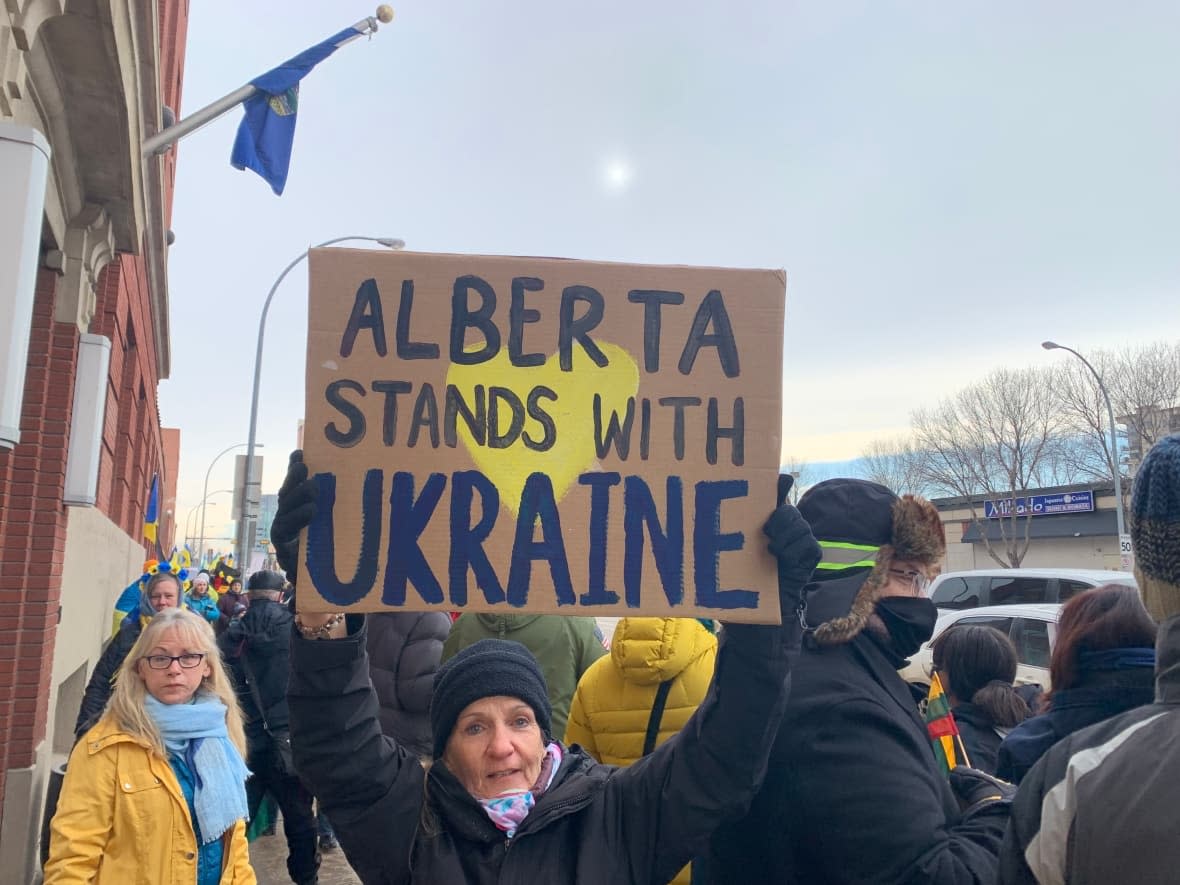 A supporter holds a sign in Edmonton at a rally held earlier this year. Alberta is expanding eligibility for support programs for newly arriving Ukrainian refugees, the government announced Monday. (Pippa Reed/CBC - image credit)