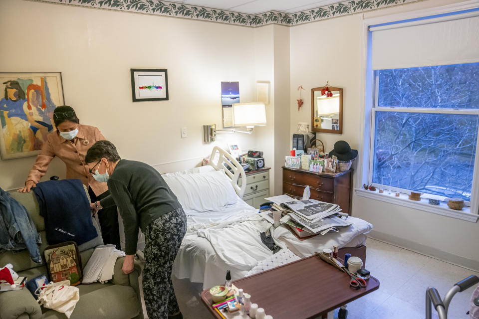 Tina Sandri, CEO of Forest Hills of DC senior living facility, left, helps resident Courty Andrews rearrange a chair in Andrews' room on Thursday, Dec. 8, 2022, in Washington. Coronavirus-related hospital admissions are climbing again in the United States, with older adults a growing share of U.S. deaths and less than half of nursing home residents up to date on COVID-19 vaccinations. (AP Photo/Nathan Howard)