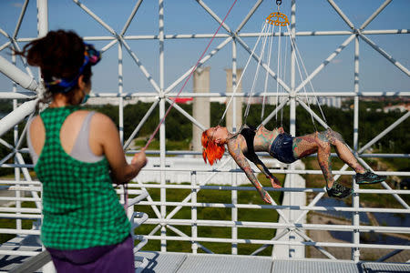 Zorana Unkovic (L), 27, holds a rope for Kaitlin, 28, from the United States as she is suspended from hooks pierced through her skin by the professional body artist Dino Helvida in Zagreb, Croatia June 7, 2016. REUTERS/Antonio Bronic