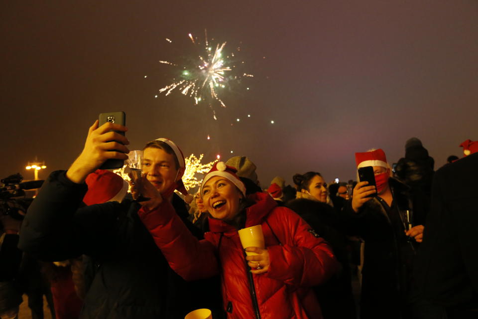 Passengers of a party bus celebrate New Year after driving through Moscow, Russia, Friday, Jan. 1, 2021. While restaurants and other entertainment venues close its doors across the country at 23:00, Muscovites look for ways to bend the coronavirus restrictions. One of them is a party bus whose owners offer to spend the New Year night touring around the city and having drinks with other strangers. (AP Photo/Alexander Zemlianichenko Jr)