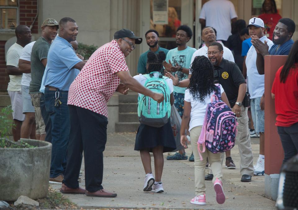 The Watch D.O.G.S. (Dads With Great Students), fathers and grandfathers of Barack H. Obama Magnet School students, cheer on each child as they head into the Jackson, Miss., elementary school on the first day of school Monday, Aug. 7, 2023.