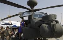 A visitor poses for a picture on a military helicopter during the Dubai Airshow November 18, 2013. REUTERS/Caren Firouz