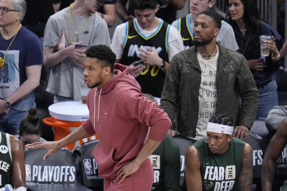Milwaukee Bucks' Giannis Antetokounmpo, left, and Damian Lillard watch during the first half of Game 4 of the first round NBA playoff basketball series against the Indiana Pacers, Sunday, April 28, 2024, in Indianapolis. (AP Photo/Michael Conroy)