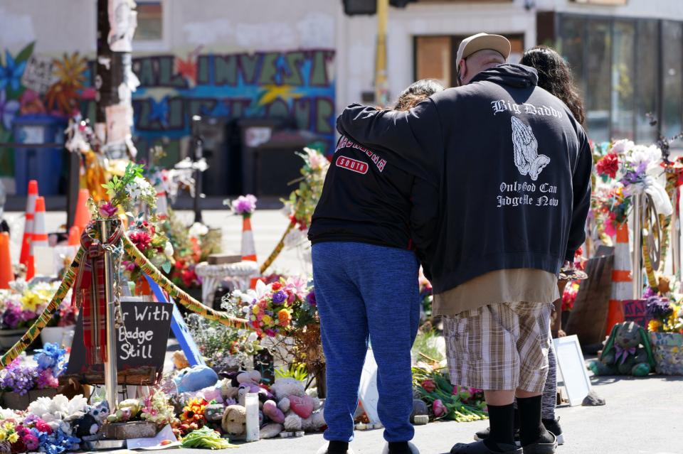 People embrace at a memorial to George Floyd at the intersection of 38th Street and Chicago Avenue in Minneapolis, where Floyd died. Community activists have blocked and occupied the intersection for nearly 10 months.