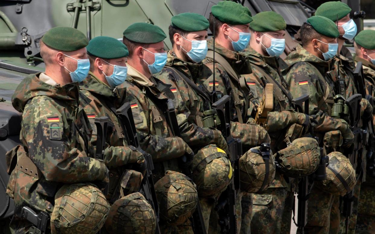 Soldiers of the German Federal Armed Forces Bundeswehr wear face maks as they attend a press presentation showing the battlefield management system (BMS) in the 37th armoured infantry regiment in Frankenberg, eastern Germany, Tuesday, May 26, 2020. A battlefield management system (BMS) is a digital system meant to integrate information acquisition and processing to enhance command and control of a military unit. The Battle Management System (BMS) has been introduced in the German armed forces base since early April 2020 and also in the Bundeswehr army since May 11, 2020. (AP Photo/Jens Meyer) - Jens Meyer/AP