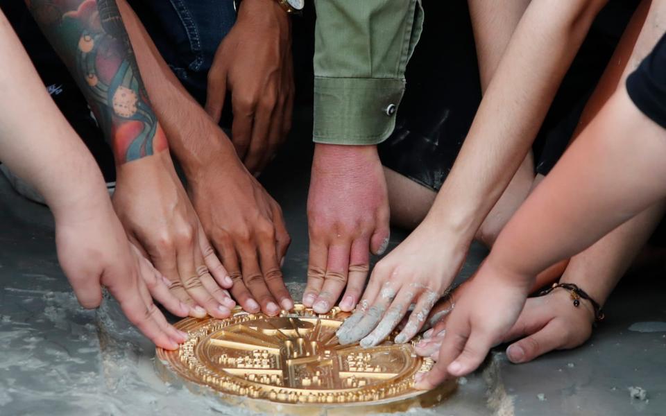 Pro-democracy student leaders install a plaque declaring "This country belongs to the people" at the Sanam Luang field during a protest in Bangkok - AP Photo/Sakchai Lalit