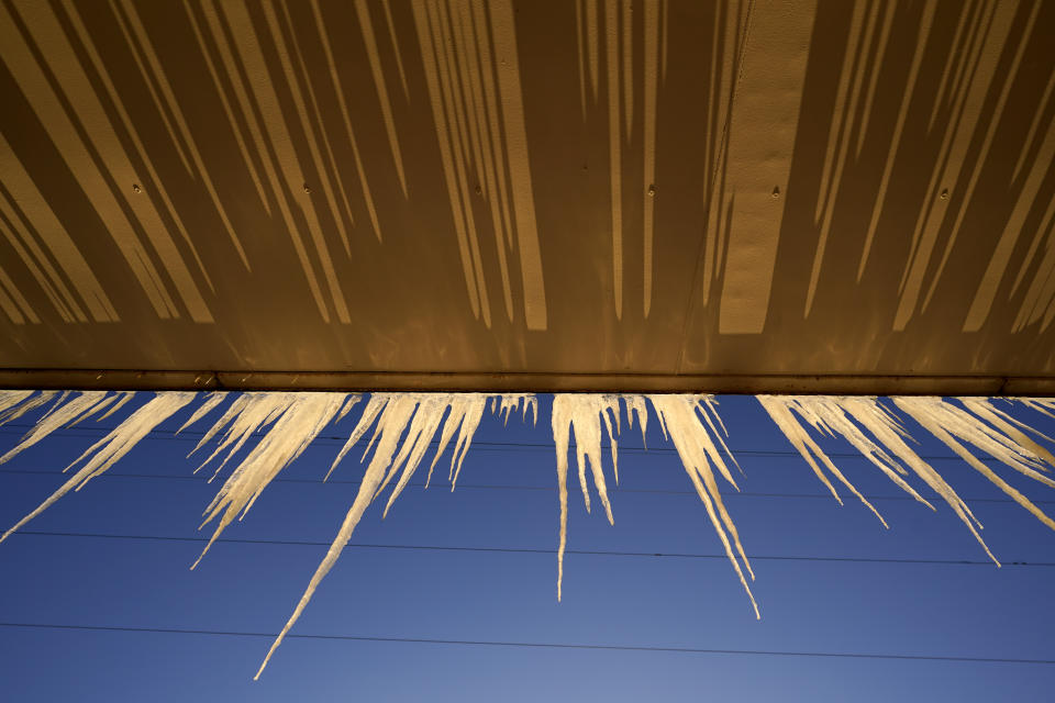 Icicles hang from a building Saturday, Feb. 13, 2021, in North Kansas City, Mo. A cold streak continues across the region with temperatures expected to drop to -13 degrees Fahrenheit by by Monday.(AP Photo/Charlie Riedel)