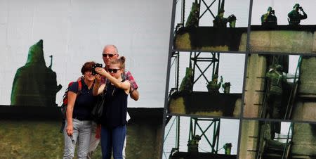 A family takes a selfie in front of the art installation "Beyond The Wall" by German artist Stefan Roloff at the backside of the East Side Gallery in Berlin, Germany, August 10, 2017. REUTERS/Hannibal Hanschke