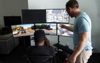 Remote operator Magi Frazier guides a self-driving vehicle from a console at the Silicon Valley headquarters of software supplier Phantom Auto, as company's co-founder Elliot Katz looks on in Mountain View