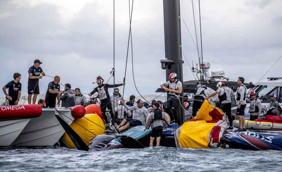 Crew from the United States' American Magic boat Patriot and Team New Zealand attempt to keep Patriot afloat after it capsized during its race against Italy's Luna Rossa on the third day of racing of the America's Cup challenger series on Auckland's Waitemate Harbour, New Zealand, Sunday, Jan. 17, 2021. (Michael Craig/NZ Herald via AP)