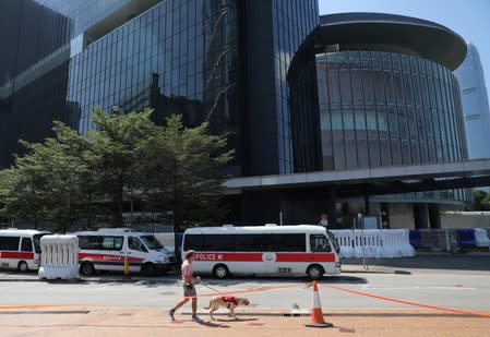 A man walks a dog as police cars are parked outside the Legislative Council Complex, in central Hong Kong