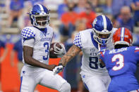 Kentucky quarterback Terry Wilson, left, looks for room to run as tight end Keaton Upshaw, center, blocks Florida defensive back Marco Wilson, right, during the first half of an NCAA college football game, Saturday, Nov. 28, 2020, in Gainesville, Fla. (AP Photo/John Raoux)