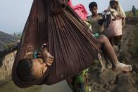 <p>A Rohingya child is carried on a sling while his family walk through rice fields after crossing the border into Bangladesh near Cox’s Bazar’s Teknaf area, Tuesday, Sept. 5, 2017. (Photo: Bernat Armangue/AP) </p>