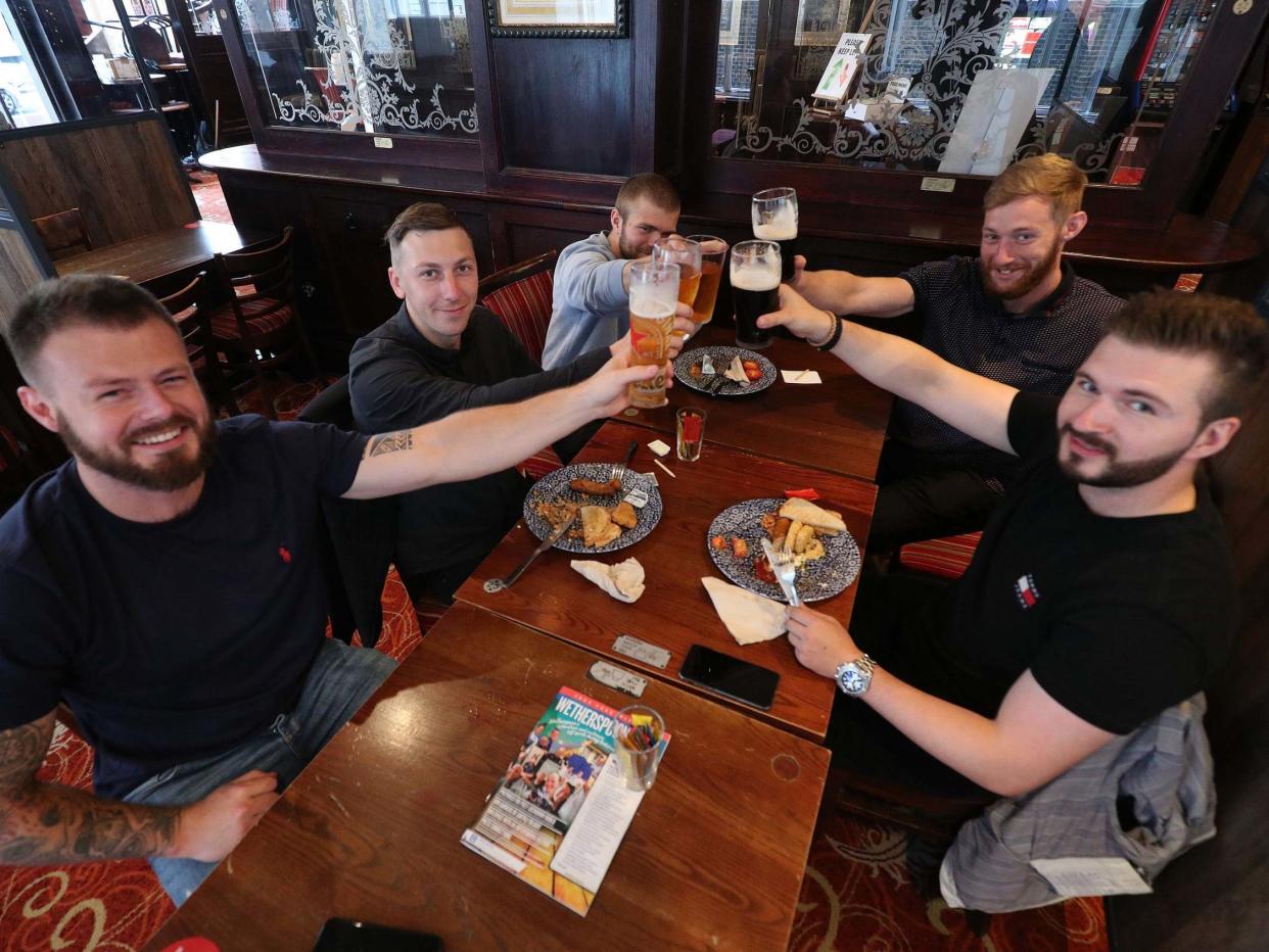 Customers give a toast with their drinks at the Shakespeare's Head in Holborn, London, as it reopens for business as coronavirus lockdown restrictions ease in England, 4 July 2020: PA