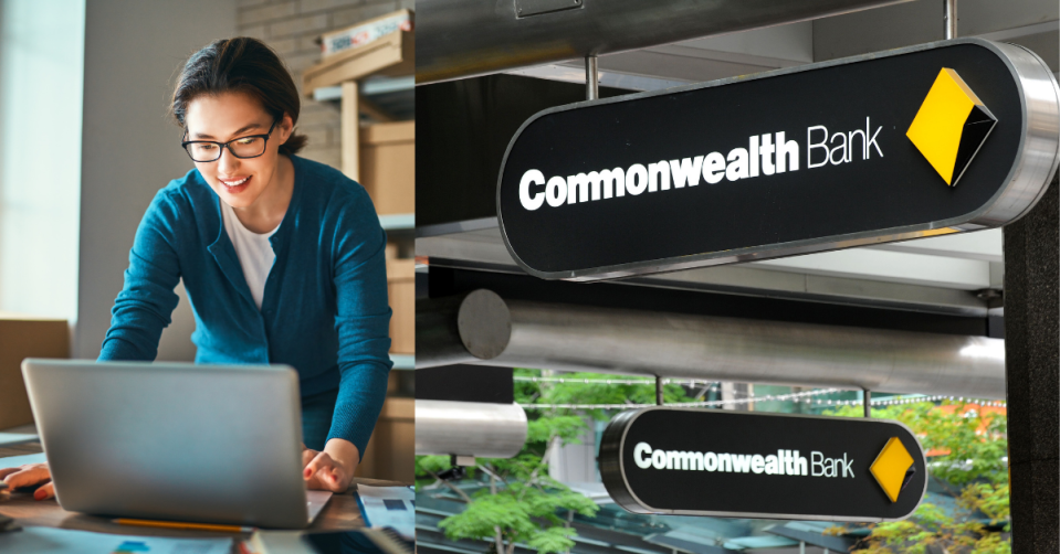 A woman works on her laptop in front of boxes to the left and the Commonwealth Bank sign to the right.