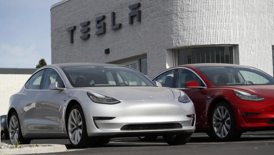 In this Sunday, April 15, 2018, photograph, unsold 2018 Model 3 Long Range vehicles sit on a Tesla dealer's lot in the south Denver suburb of Littleton, Colo. (AP Photo/David Zalubowski)