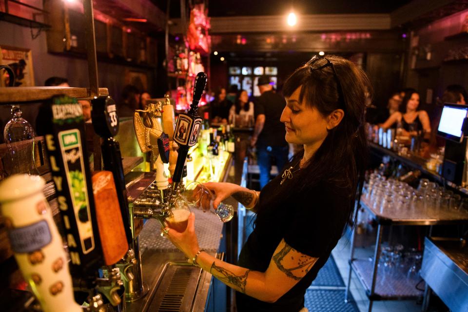 A bartender pours beers for fully vaccinated customers at the bar inside Risky Business, that was once The Other Door but closed during the Covid-19 pandemic in the North Hollywood neighborhood of Los Angeles, California on May 21, 2021. - In order to go inside Risky Business, members must present their original vaccination card after being fully vaccinated, paying a small membership fee, signing a risk release form with penalties for lying, and waiting a full two weeks after competing their shots. While the policy is strict, once inside customers can enjoy an experience knowing that everyone else has been 100-percent vaccinated with an lively pre-pandemic atmosphere with people up close and personal - talking, hugging, playing pool and drinking without rules for masks or social distancing. (Photo by Patrick T. FALLON / AFP) (Photo by PATRICK T. FALLON/AFP via Getty Images)