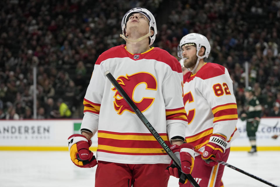 Calgary Flames center Yegor Sharangovich, front, looks at a replay after a tripping penalty called on the Flames during the third period of an NHL hockey game against the Minnesota Wild, Thursday, Dec. 14, 2023, in St. Paul, Minn. (AP Photo/Abbie Parr)