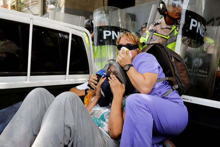 Women try to protect themselves from tear gas as security forces clash with demonstrators during an opposition rally in Caracas, Venezuela. REUTERS/Carlos Garcia Rawlins