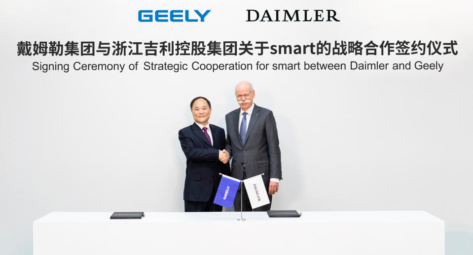 The two executives are standing before a banner that reads, in English and Chinese, "Signing Ceremony of Strategic Cooperation for Smart between Daimler and Geely."