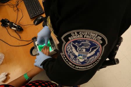 FILE PHOTO: A woman who is seeking asylum has her fingerprints taken by a U.S. Customs and Border patrol officer at a pedestrian port of entry from Mexico to the United States, in McAllen, Texas, U.S., May 10, 2017. REUTERS/Carlos Barria/File Picture