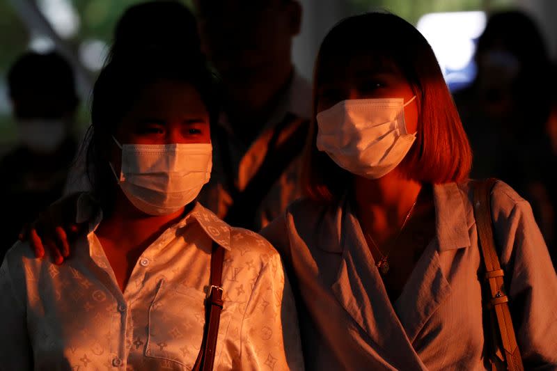 Commuters wearing protective masks walk during the afternoon rush hour in Bangkok, Thailand