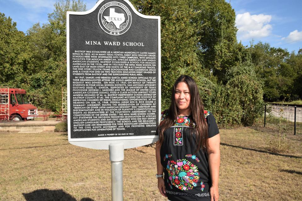 Linda Quiroz stands next to the Texas Historical Commission plaque on Bastrop’s North Main Street commemorating the site of the former Mina Ward School for Hispanic students and a landmark federal court case that helped end educational discrimination against Hispanic students in Texas.