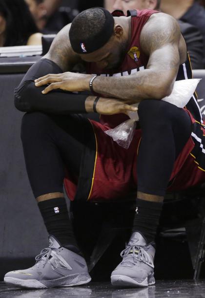 LeBron James sits on the bench with ice on his leg. (AP)