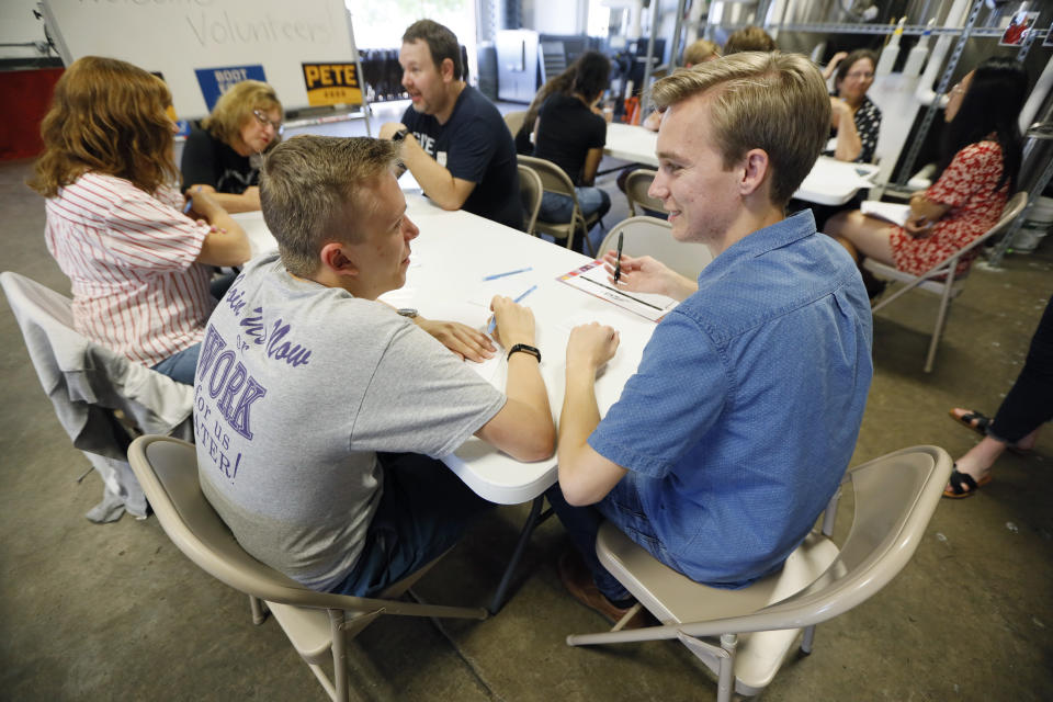 Kyle Rittmueller, left, and Michael Paulson, right, supporters of Democratic presidential candidate Pete Buttigieg, participate in a "relational phone bank" at a local brewery, Thursday, Aug. 29, 2019, in West Des Moines, Iowa. The two Drake University students were part of a group that worked their smartphones calling and texting friends to test their interest the candidate. Buttigieg is well behind his better known rivals in Iowa who have spent months building a deep organizational structure in the state that marks the first test for the Democratic presidential nomination. But thanks to his campaign taking in nearly $25 million in contributions in the last quarter, money that he is using to help create an army of peer-to-peer foot soldiers, Buttigieg is rapidly trying to catch up. (AP Photo/Charlie Neibergall)