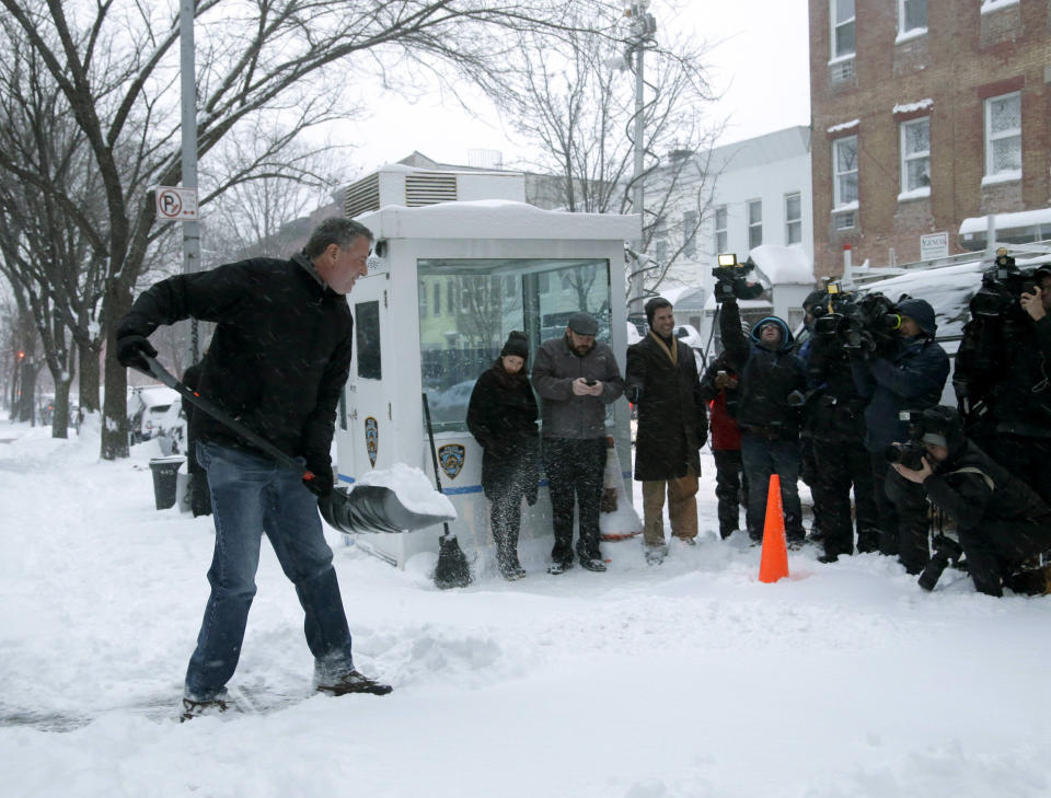 FILE- In this Jan. 3, 2014 file photo, New York City Mayor Bill de Blasio shovels the sidewalk in front of his New York City home in front of the media gathered to record the event. Experts say de Blasio, a former political operative, is using carefully chosen events and images to cultivate the appearance of being an average New Yorker focused on fixing the city's widening income inequality. (AP Photo/Seth Wenig, File)