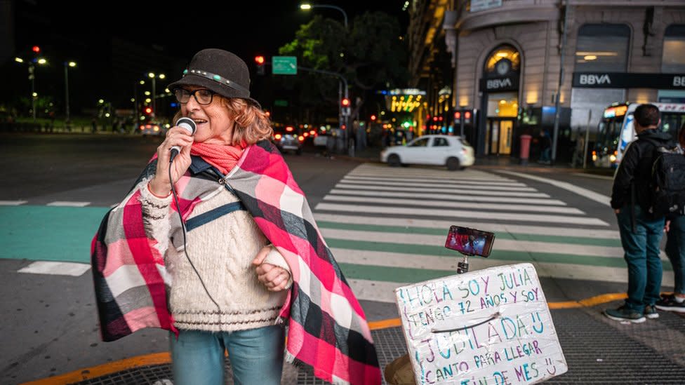 Julia stands on a street singing