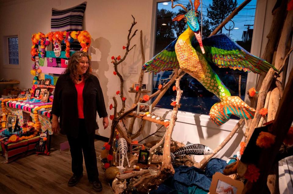 Melinda Velasco smiles at her ofrenda made with found peices of wood to honor animals who died in recent floods during a Dia de los Muertos art reception at the Center Street Gallery on Thursday, Oct. 19, 2023.