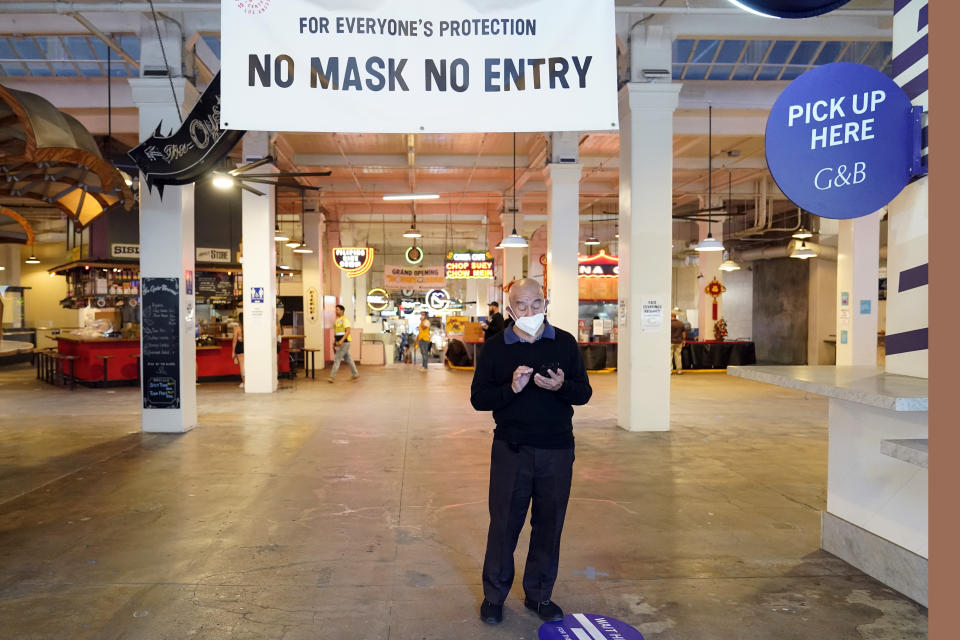 FILE - In this Nov. 16, 2020, file photo, a sign points to a mask mandate at the Grand Central Market in Los Angeles. Gov. Gavin Newsom announced Monday, Nov. 16, 2020, that due to the rise of COVID-19 cases, some counties have been moved to the state's most restrictive set of rules, which prohibit indoor dining. The new rules begin Tuesday, Nov. 17. (AP Photo/Marcio Jose Sanchez, File)
