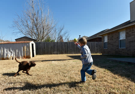 Stephanie Oakley's son, who suffers from a rare form of cancer, plays with his dog at his family's new home in Oklahoma City, Oklahoma, U.S. November 26, 2018. REUTERS/Nick Oxford