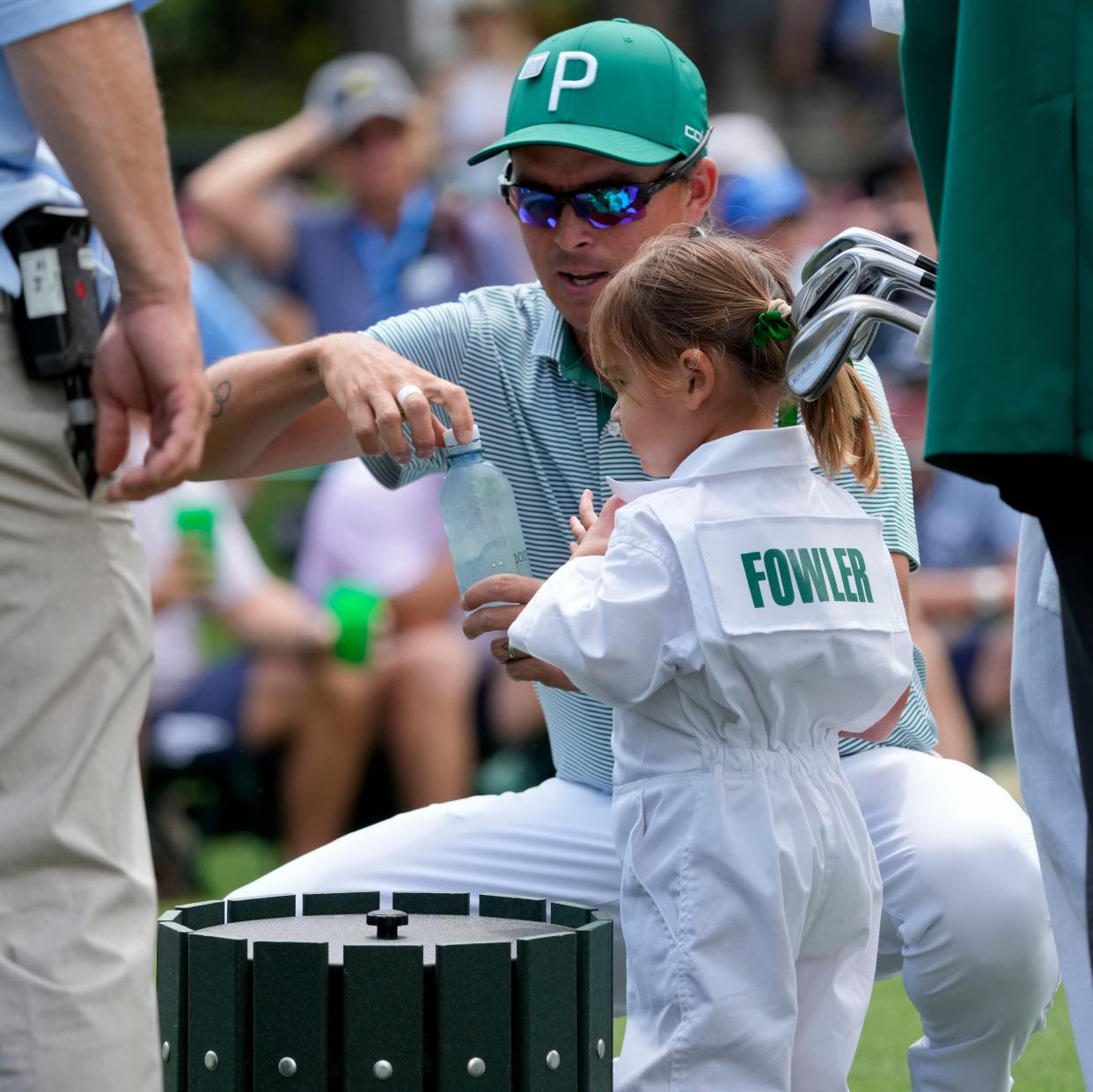 Rickie Fowler gets his daughter, Maya, a bottle of water during the Par 3 Contest at Augusta National Golf Club.