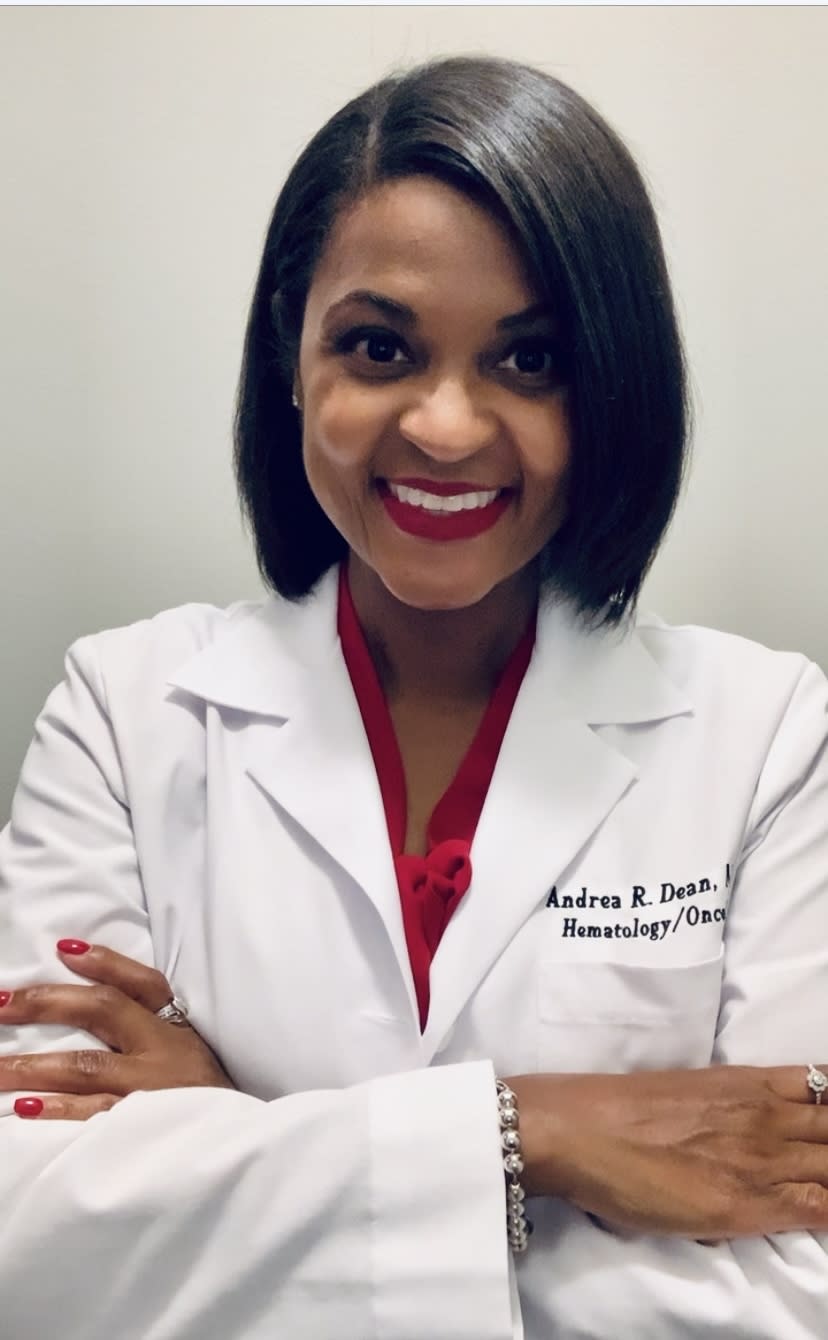 Andrea R Dean, MD, posing in a white lab coat, smiling at the camera with crossed arms