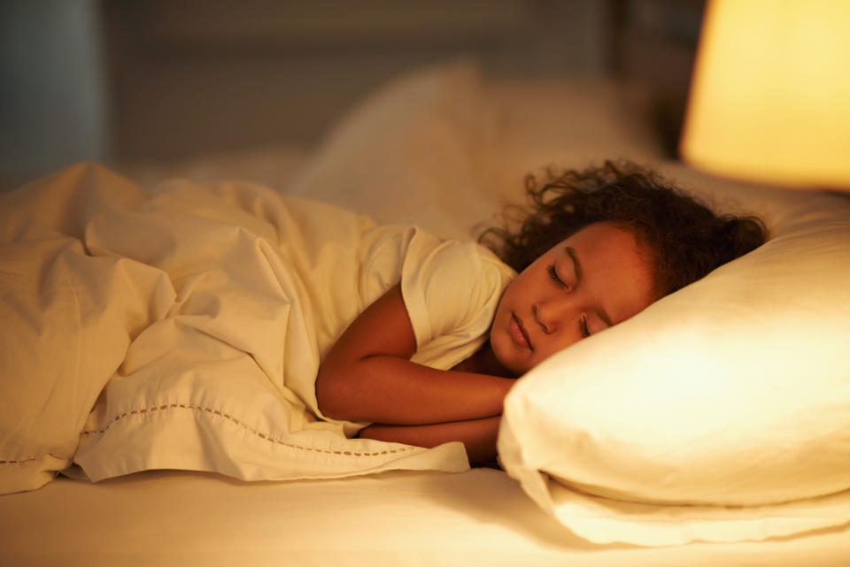 A cute little girl fast asleep in a double bed