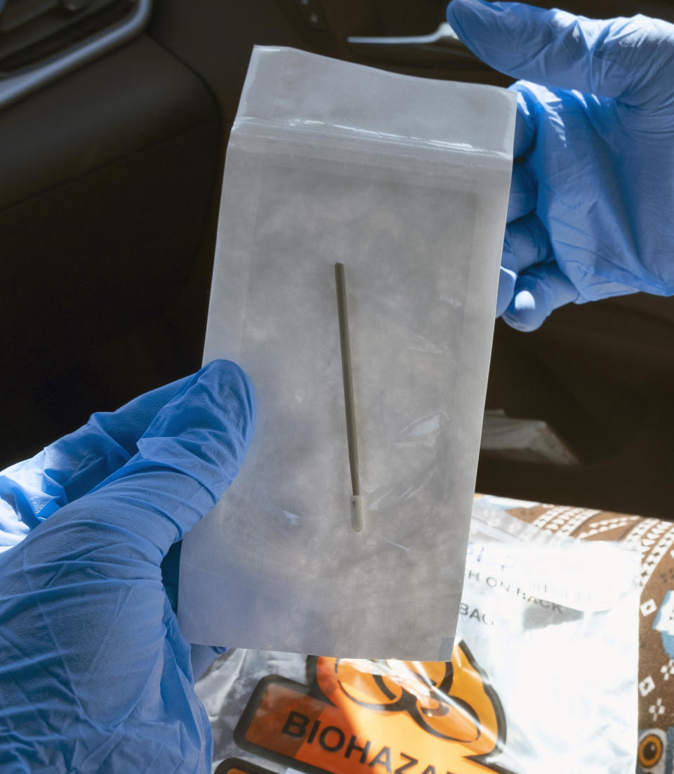 In this Wednesday, May 6, 2020 photo a patient unpackages a swab to be used for a self administered coronavirus test at a drive through testing site in a parking lot in the Woodland Hills section of Los Angeles. The city of Los Angeles is providing free coronavirus tests to anyone who wants one regardless of whether they have symptoms. The offer reflects a parting with state guidelines after the mayor partnered with a startup testing company. The test the city is offering is easier to administer and doesn't require the scarce supplies that have created bottlenecks for expanded testing across California. (AP Photo/Richard Vogel)