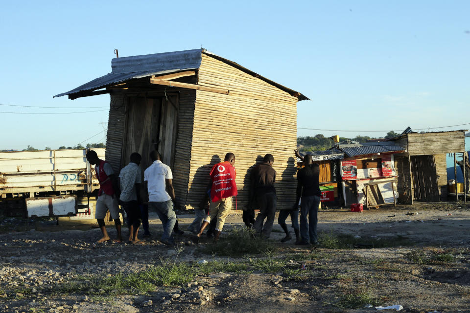 Men carry a mobile shop to safer ground in Pemba city on the northeastern coast of Mozambique, Saturday, April, 27, 2019. Cyclone Kenneth arrived late Thursday, just six weeks after Cyclone Idai ripped into central Mozambique and killed more than 600 people.Authorities are urging people to move immediately to higher ground as flooding and mudslides are feared in the wake of Cyclone Kenneth .(AP Photo/Tsvangirayi Mukwazhi)