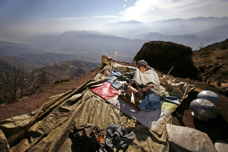 FILE PHOTO: A Kashmiri earthquake survivor uses her sewing machine to sew up winter clothes, outside her shelter on the mountainous Buttlian area, some 25 km northeast of the earthquake-devastated city of Muzaffarabad in Pakistan-administered Kashmir, January 26, 2006. REUTERS/Yannis Behrakis/File photo