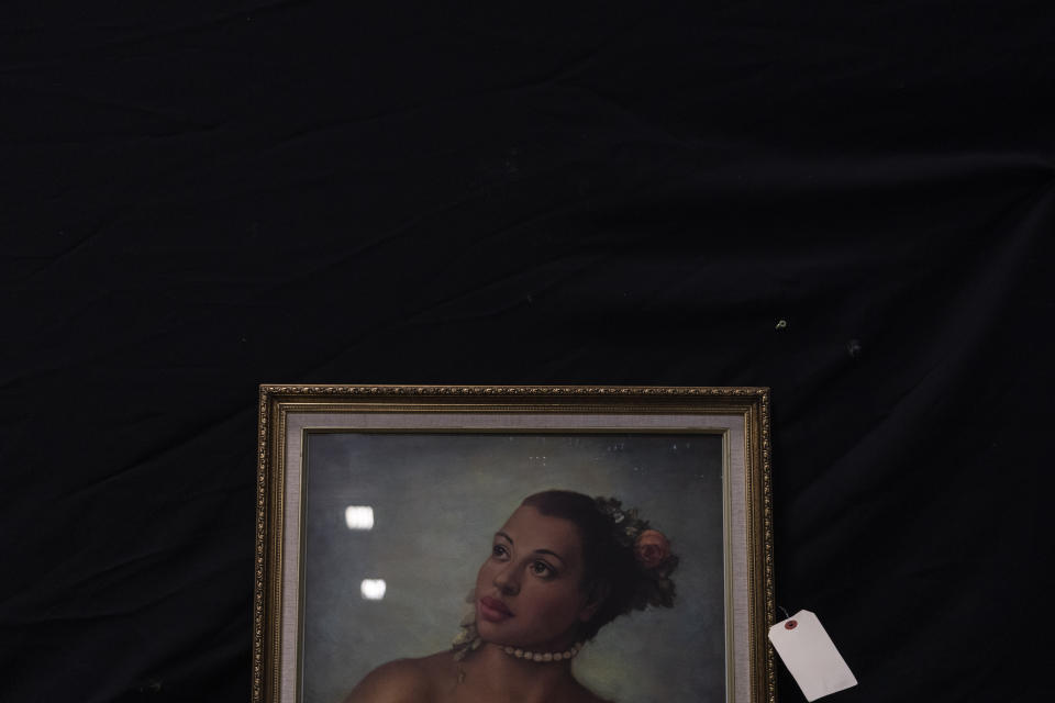 A painting is propped against a wall to be auctioned off at a Los Angeles County warehouse in the County of Los Angeles, Calif., Thursday, June 15, 2023. The warehouse is filled with belongings from people's estates, including anything from doll collections and clothes to framed paintings, china dishware, washing machines, and cars, much of it housed in massive wooden crates. The items will be auctioned off to the public to pay off the estates' debts and cover burial or cremation services. (AP Photo/Jae C. Hong)