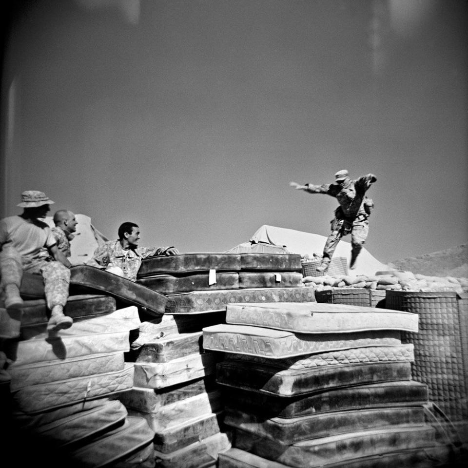 Soldiers watch Specialist Adam Ramsey (right) jump onto a pile of mattresses in the south of Logar Province, Afghanistan. September 2009.