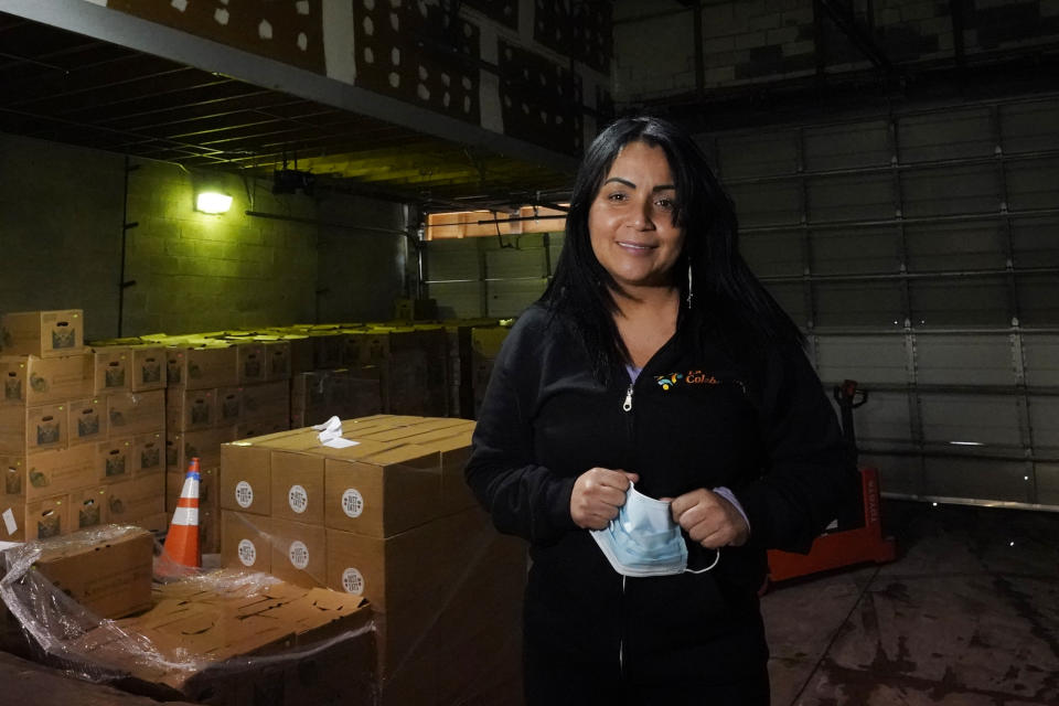 Gladys Vega, executive director of La Colaborativa, poses inside the nonprofit's food pantry warehouse in Chelsea, Mass., Feb. 10, 2021. Vega's organization has partnered with a community health center to launch a public vaccination site at its office on Broadway, the city’s bustling main street. (AP Photo/Elise Amendola)