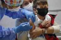 A young boy grimaces as he is vaccinated against COVID-19 in Rome, Thursday Dec. 16, 2021 as the program to vaccinate children under the age of 12 continues. (Cecilia Fabiano/LaPresse via AP)