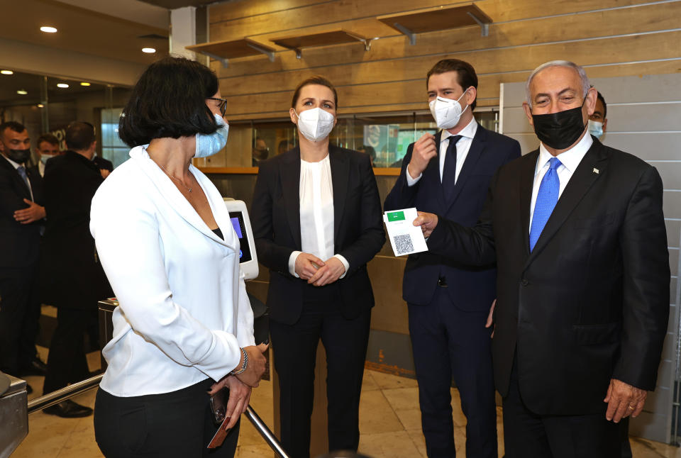 FILE - In this March 4, 2021, file photo, Israeli Prime Minister Benjamin Netanyahu, right, holds a "Green Pass," for citizens vaccinated against COVID-19, as he visits a fitness gym with Austrian Chancellor Sebastian Kurz, second right, and Danish Prime Minister Mette Frederiksen, left, to observe how the pass is used, in Modi'in, Israel. While the country's "green pass" system has been successful in the areas of leisure and entertainment, it has proved to be more complicated in the workplace, where stakes are higher. (Avigail Uzi/Pool via AP, File)