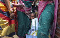 A child of a migrant worker waits with others for transportation to return to their home state, in Hyderabad, India, Thursday, May 28, 2020. Rural villages across India are seeing an increase in cases with the return of hundreds of thousands of migrant workers who left cities and towns where they were abandoned by their employers after having toiled for years building homes and roads. India sees no respite from the coronavirus caseload at a time when the two-month-old lockdown across the country is set to end on Sunday. (AP Photo/Mahesh Kumar A.)