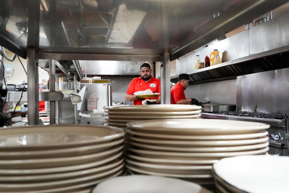 Chefs Vicente Vargas, left, and Ricky Vargas prepare food as plates wait to be filled and served.